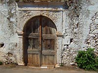 Wooden arch door in old stone
      wall.