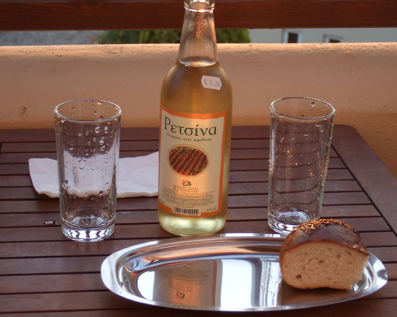 Вечер. На балконе деревянный стол.
      На столе бутылка вина Рецина, два стакана и ломоть хлеба. 
