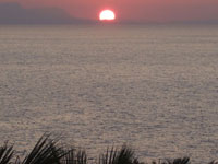 Солнце опускается за край острова
      в море