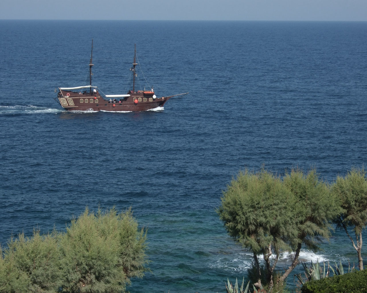 An old fashion pirates boat
      on the blue sea.